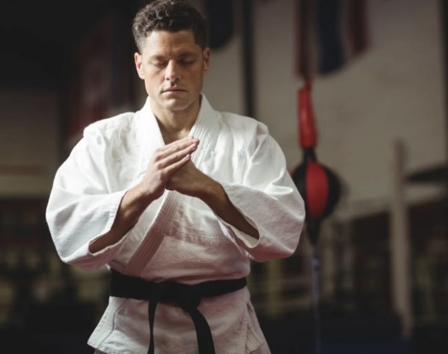 Confident martial artist standing focused in a training gym symbolizing masculine discipline and inner strength